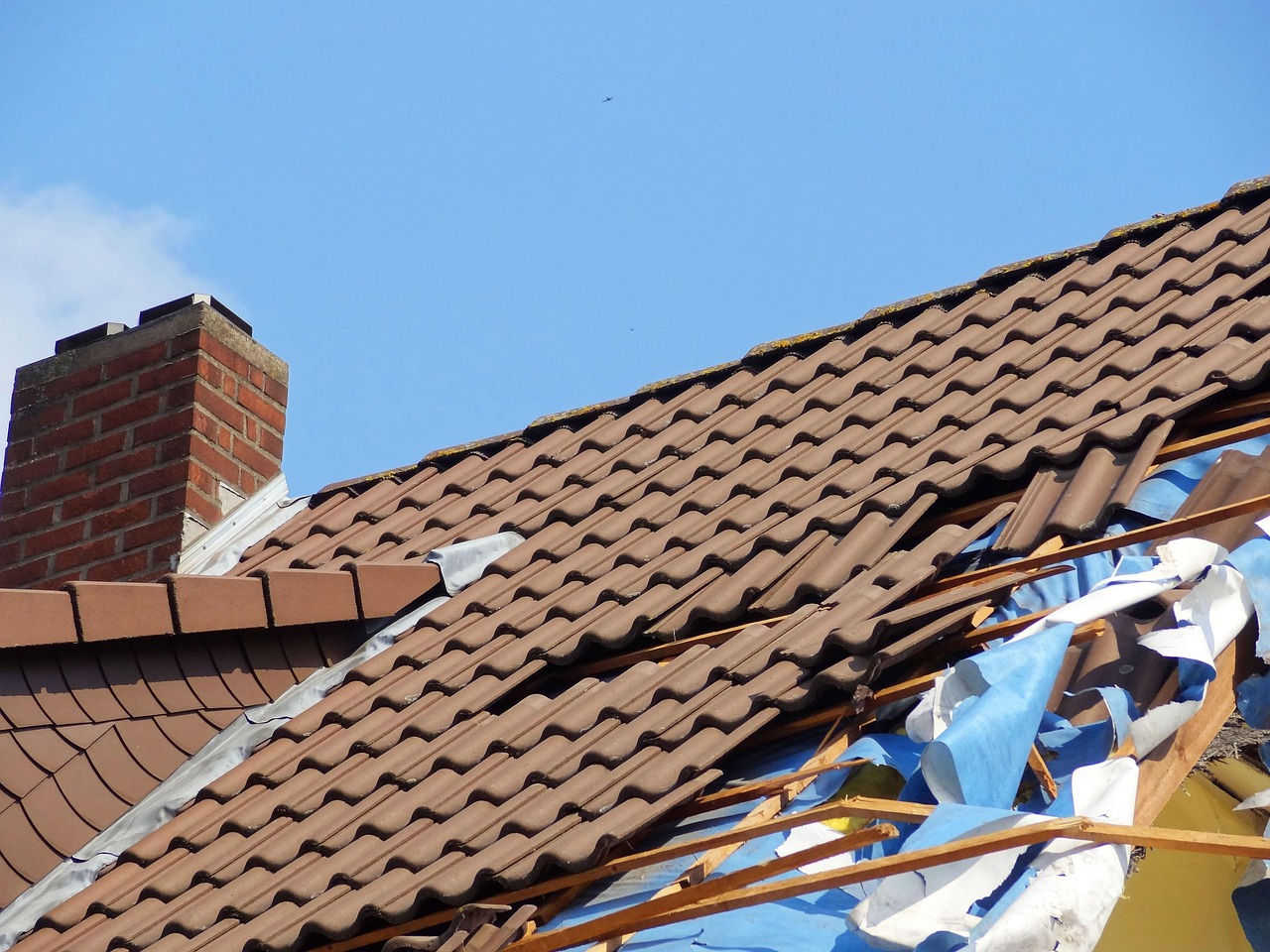 A residential roof with visible storm damage including missing shingles and damaged sections